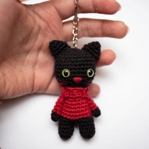 dłoń trzymająca brelok Catorable w formie czarnego kota w czerwonym golfie