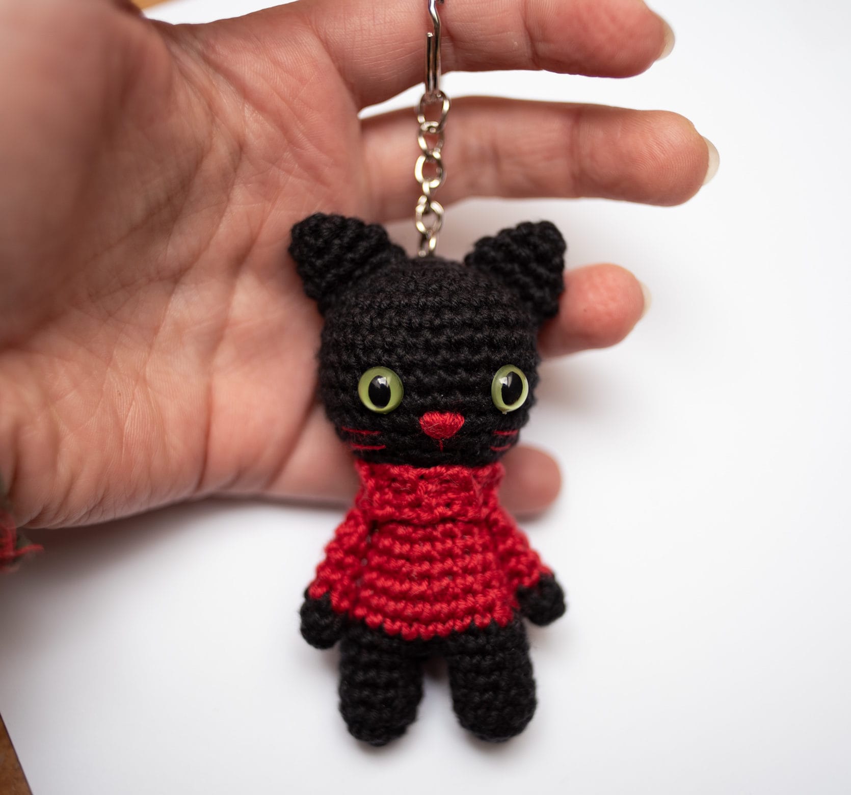 dłoń trzymająca brelok Catorable w formie czarnego kota w czerwonym golfie