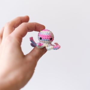 ośmiorniczka dla kota zbliżenie na ludzką dłoń trzymającą różową zabawkę na białym tle