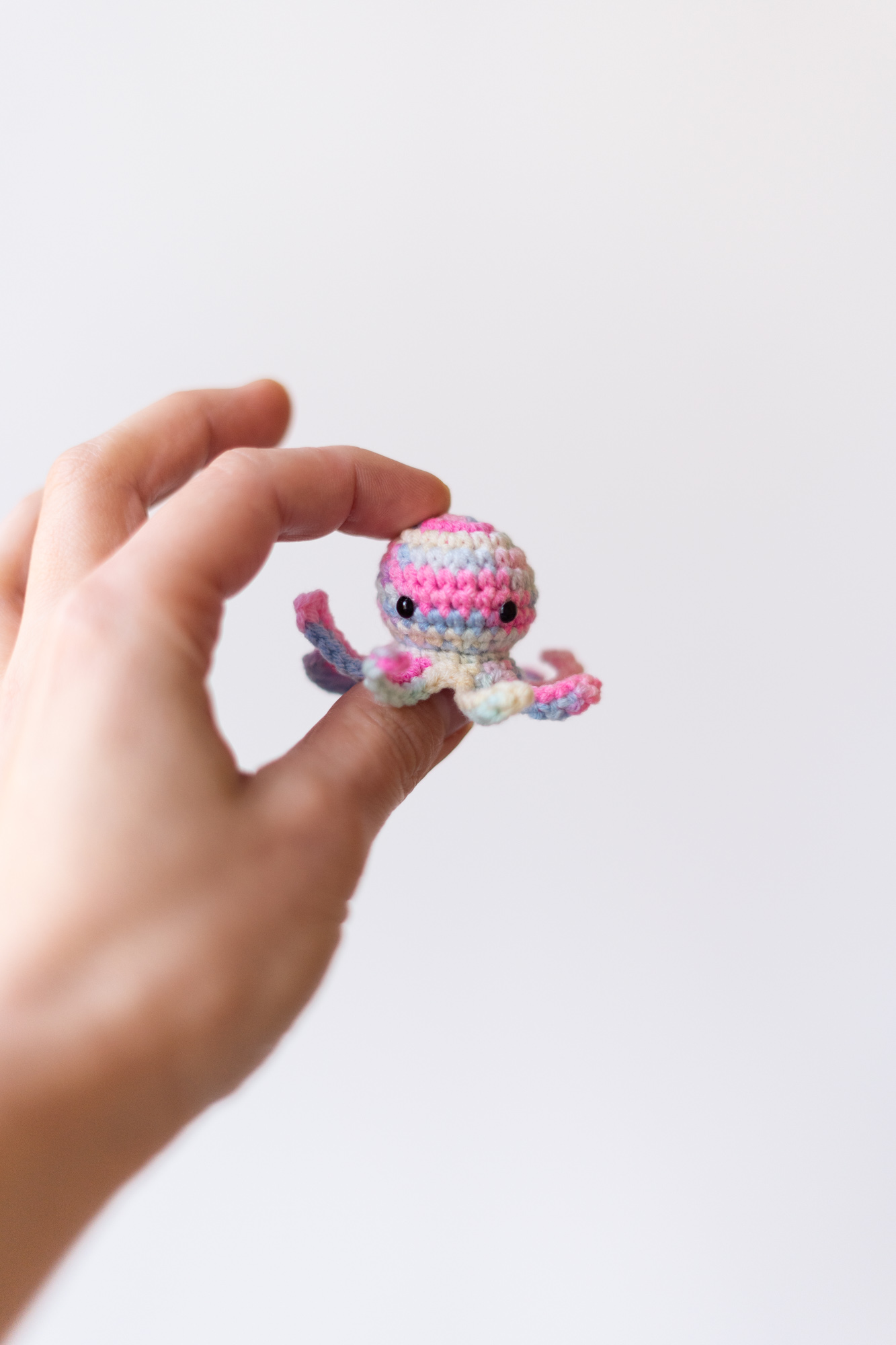 ośmiorniczka dla kota zbliżenie na ludzką dłoń trzymającą różową zabawkę na białym tle