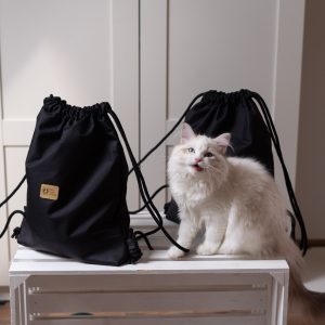 dwa czarne plecaki z tkaniny wodoodpornej prezentowane przez kota w manufakturze Catorable