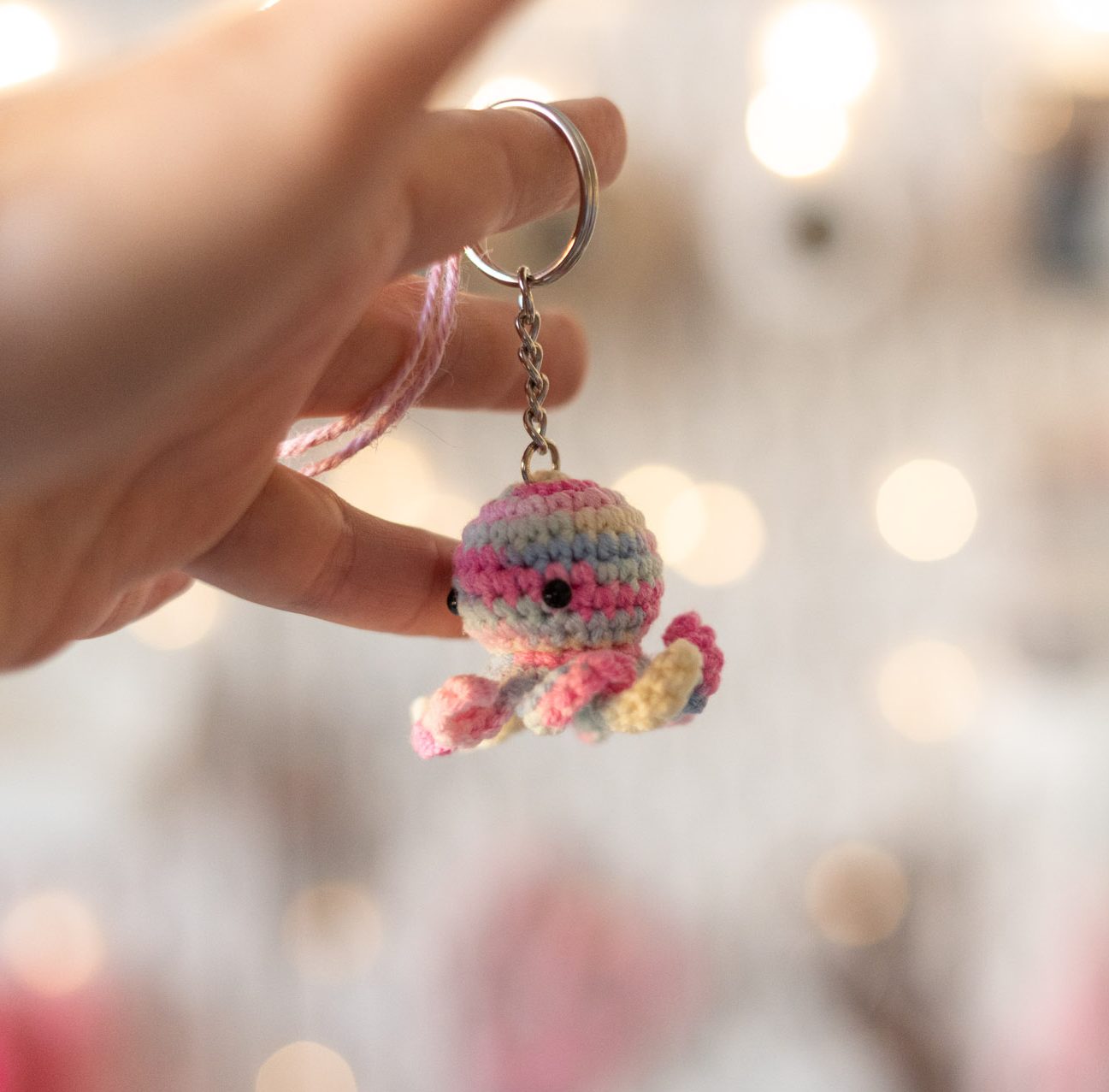 Różowe brelok ośmiorniczka na tle światełek i przyborów w pracowni Catorable