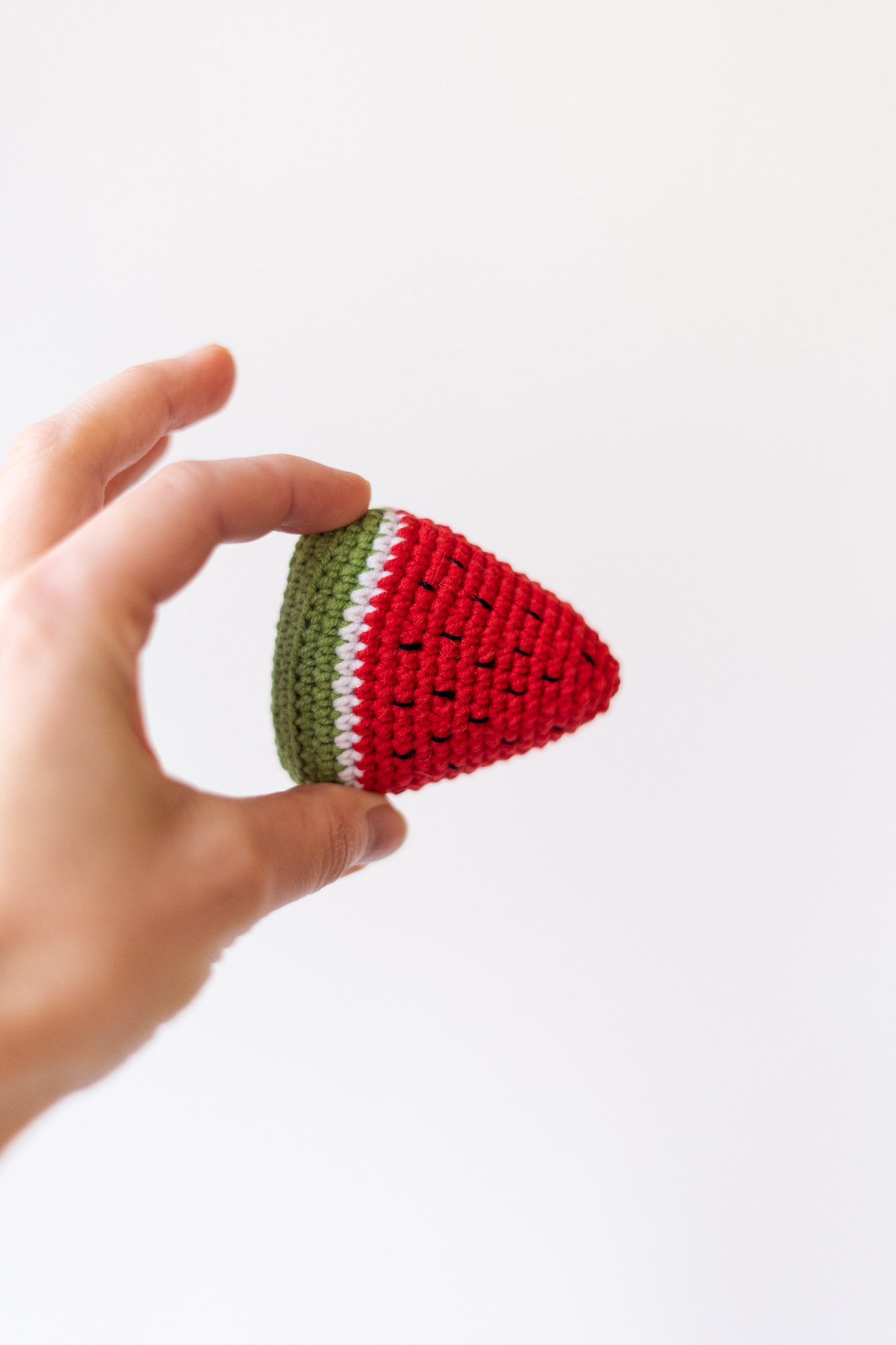 Zabawka dla kota arbuz z kocimiętką i walerianą trzymany w dłoni